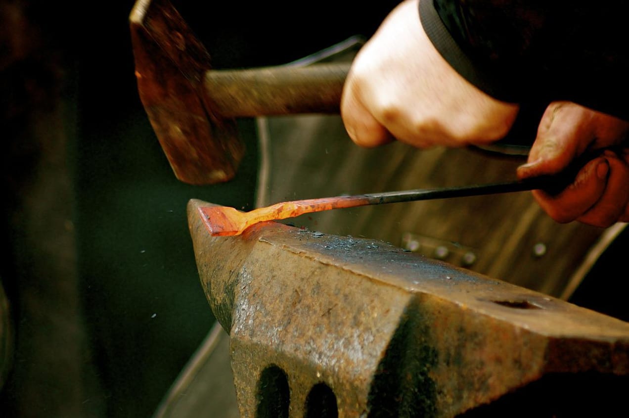Blacksmith striking a piece of hot metal on an anvil