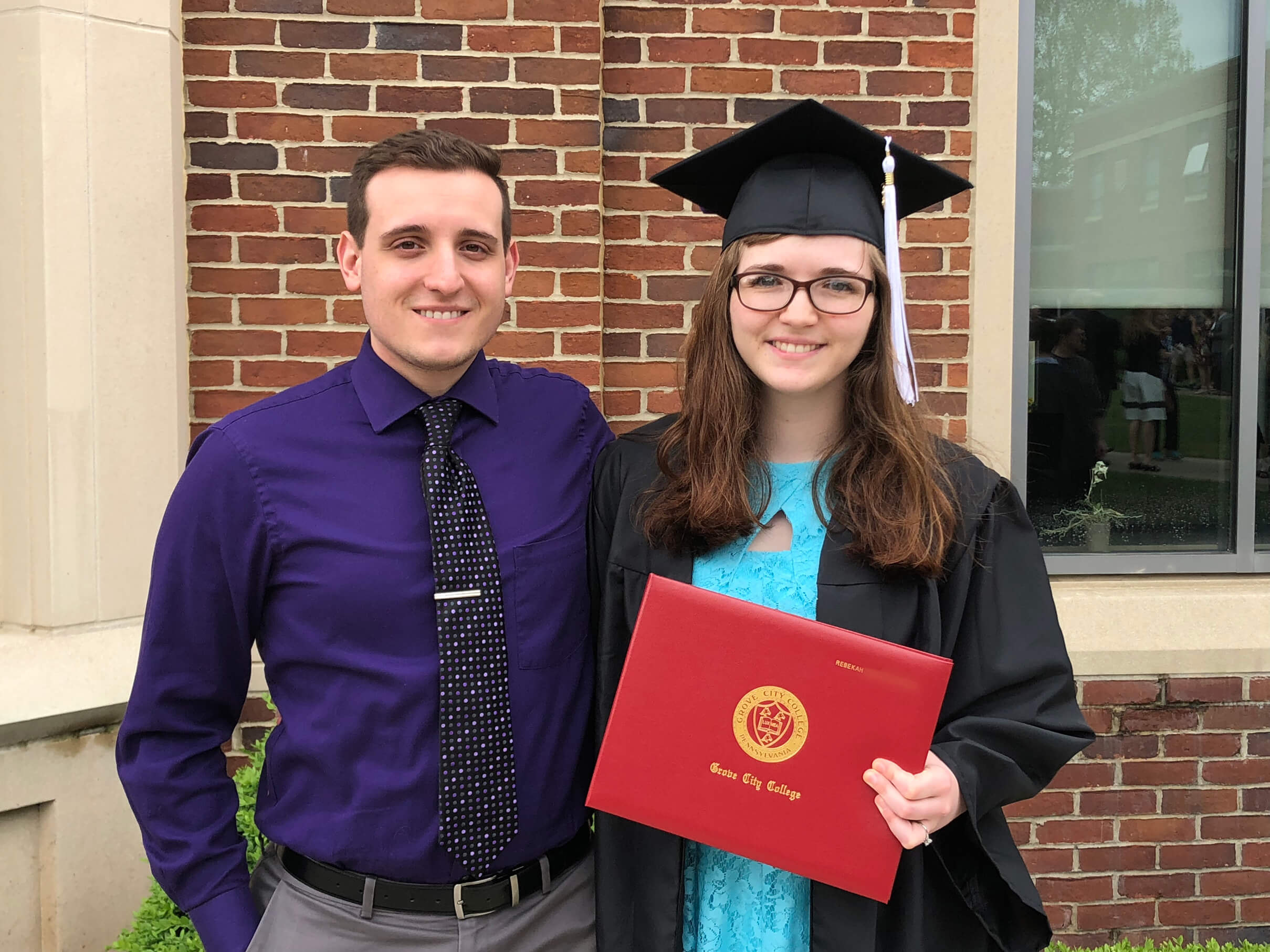 Rebekah holding her GCC diploma on her graduation day with her husband John