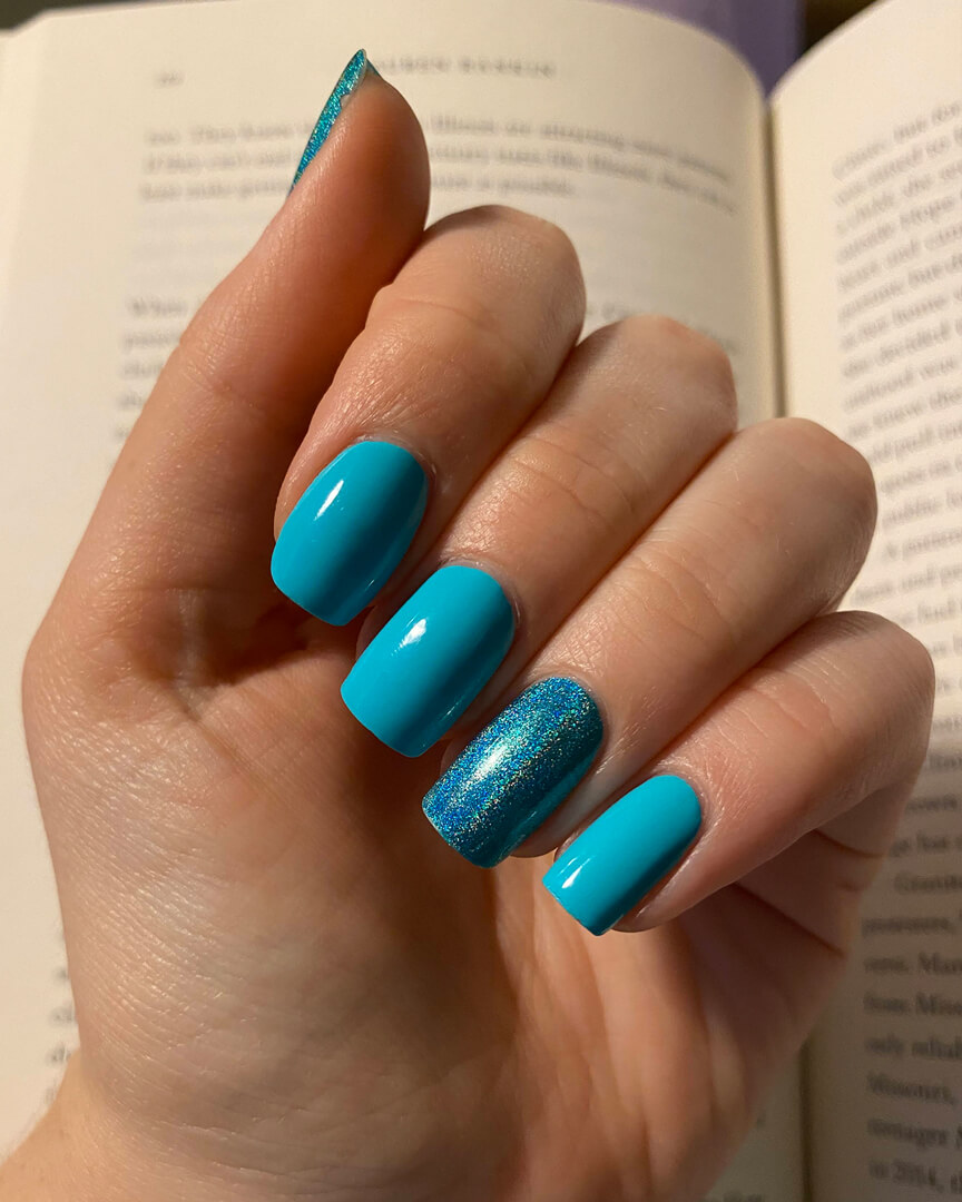 Rebekah is wearing cyan creme nail polish, with an accent nail on her ring finger which has holographic cyan polish 