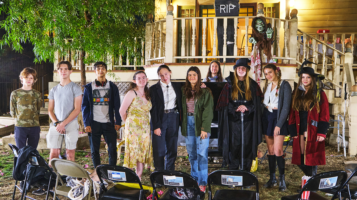 Evolve youth group teens in Halloween costumes poses in front of a house decorated for Halloween